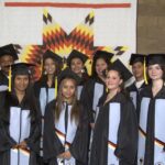 Nine Indigenous students wearing caps and gowns
